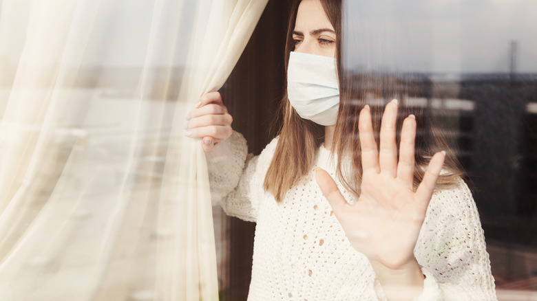 Woman with mask looking out window