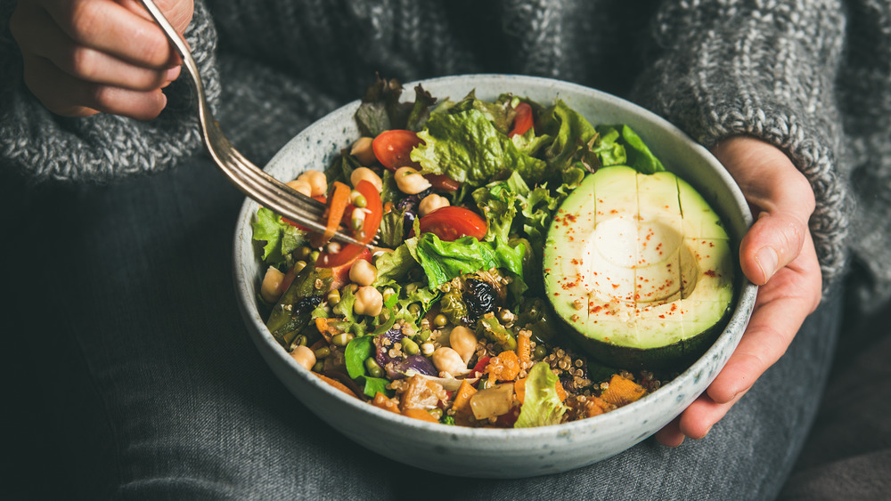 Woman holding a bowl salad on her lap  