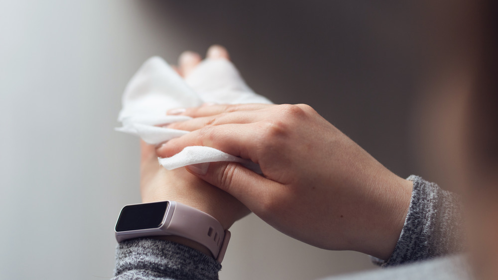 A woman wiping her hands with a cleaning wipe