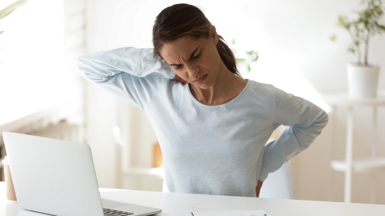 Women at a desk rubbing her back