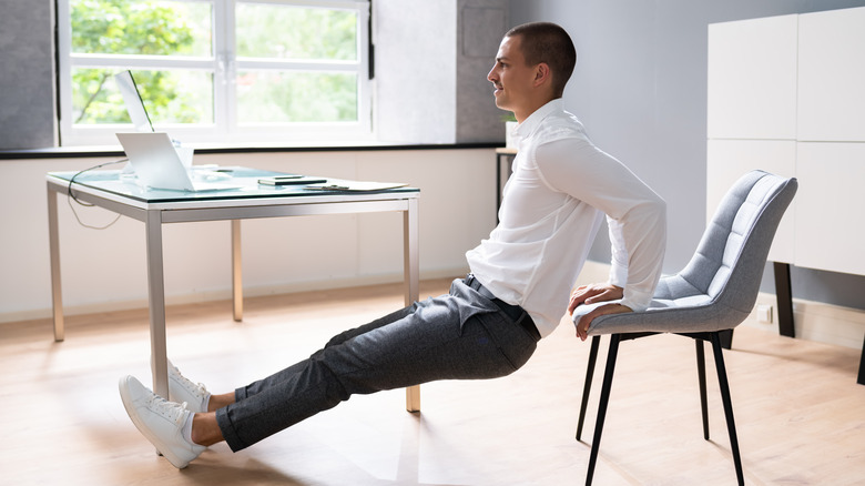 Man stretching his legs while holding a chair