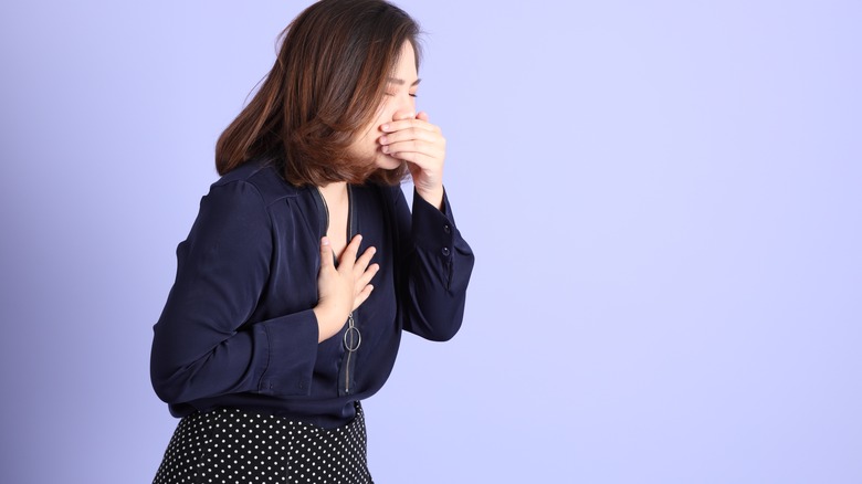 woman sneezing purple background