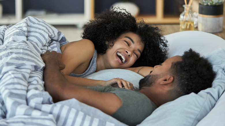 Laughing couple laying in bed