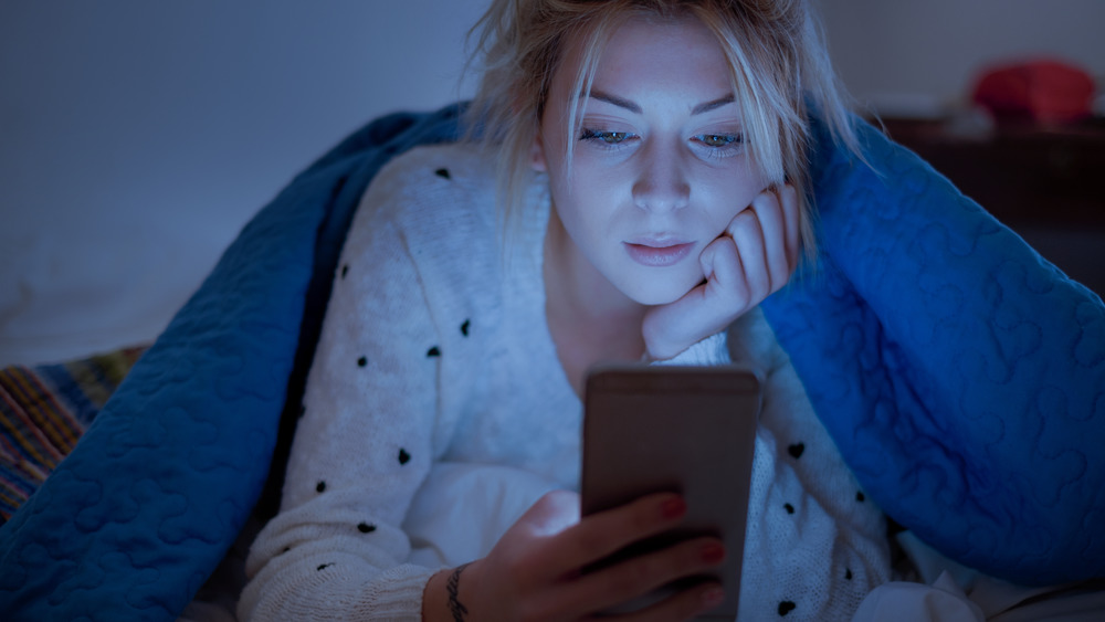 Woman holding phone in bed