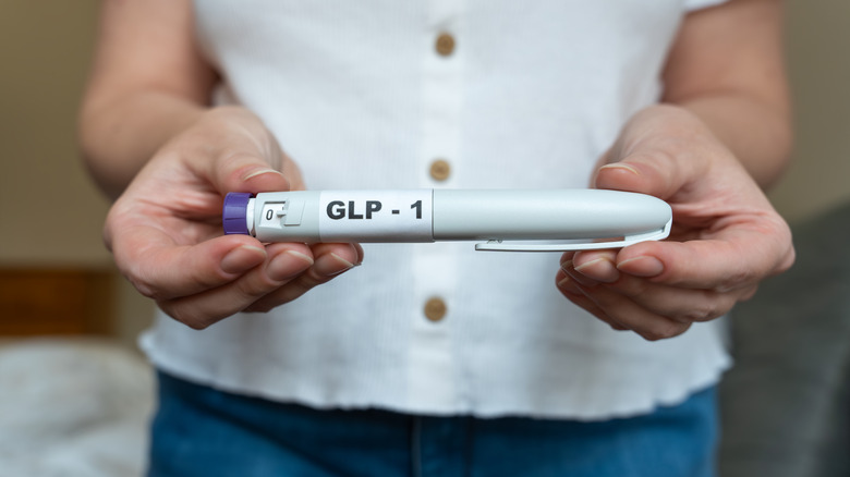 woman holding an injector pen for a GLP-1 drug