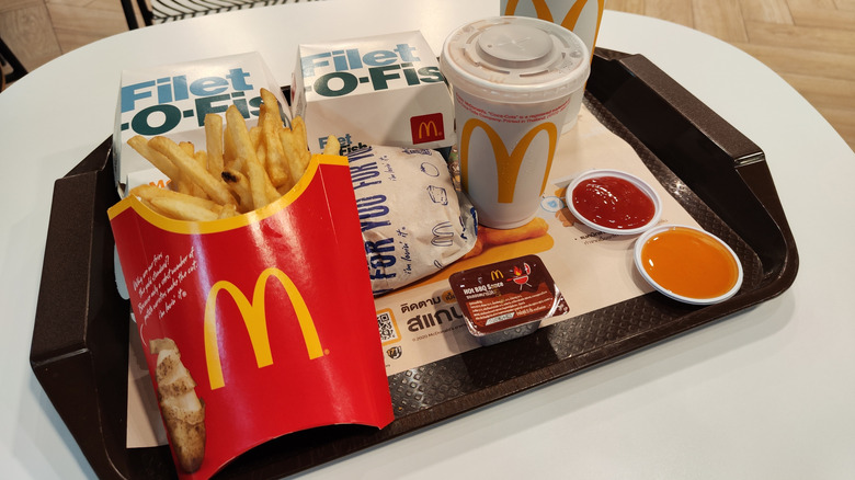 Two Filet-O-Fish sandwiches, a side of fries, a hamburger, soft drinks, and dipping sauces on a McDonald's tray