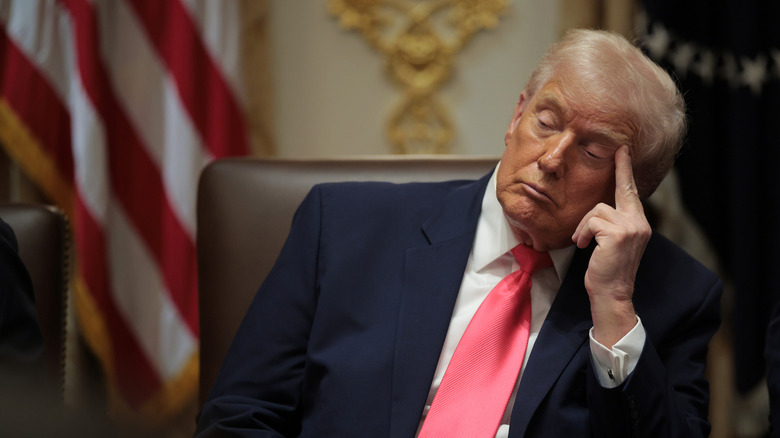 President Donald Trump in a red USA hat and black coat outside.