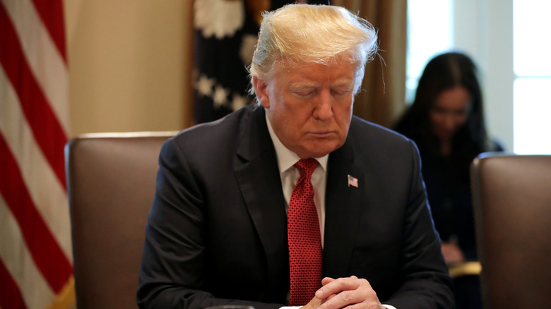 Donald Trump closes his eyes during a prayer before a meeting of his cabinet in the Cabinet Room at the White House October 17, 2018.