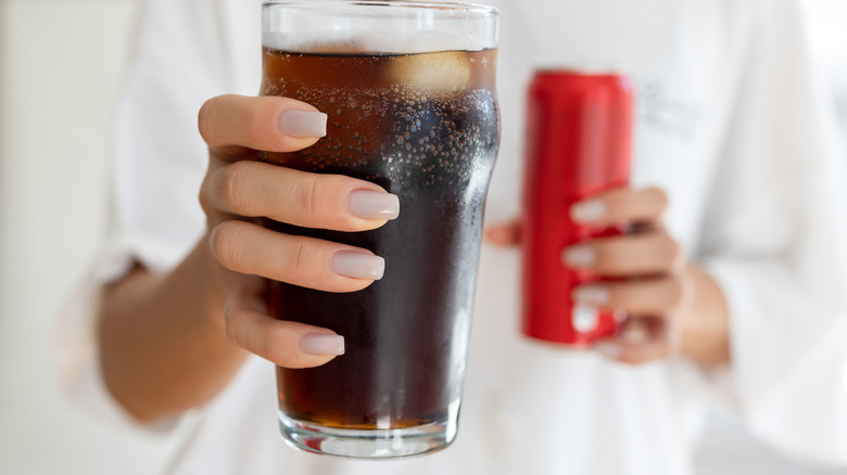 A hand holding a glass of cola
