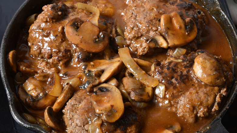 Salisbury steak simmering in cast iron skillet
