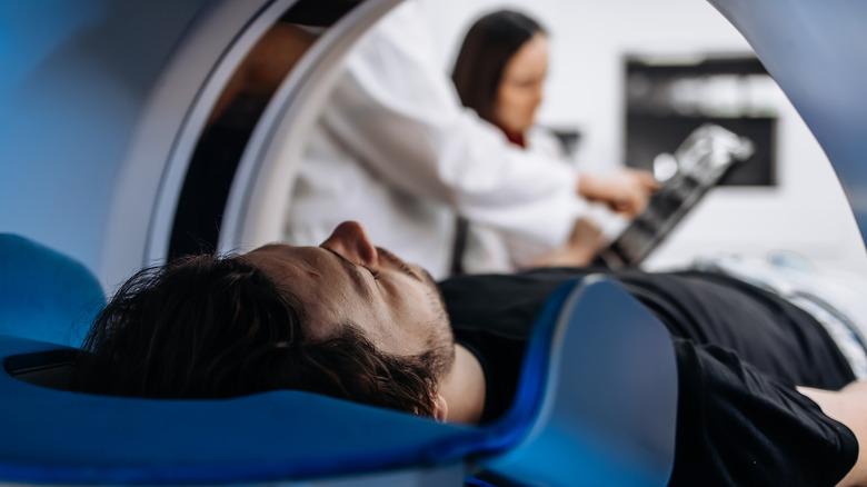man in MRI scan machine with tech in background