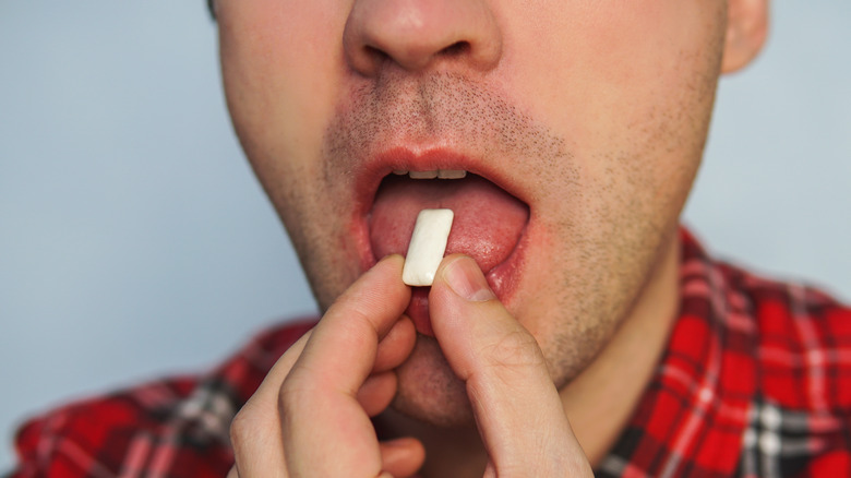 Guy putting gum in his mouth