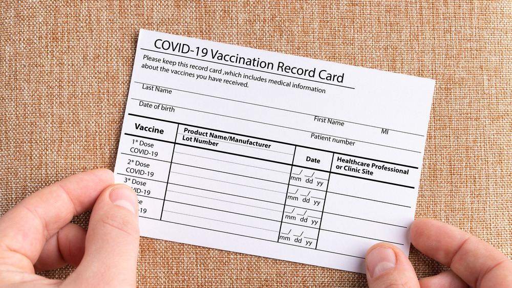 Hands holding a COVID-19 vaccination card