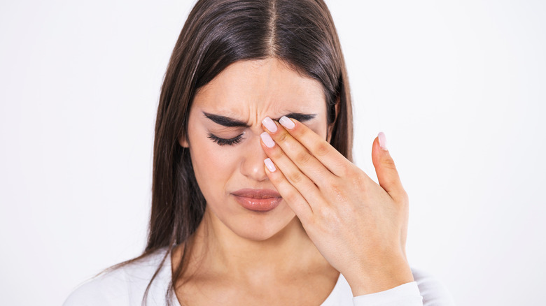 young woman rubbing her eye with a manicured hand 