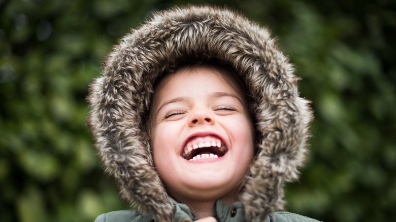 Child in furry hood smiling