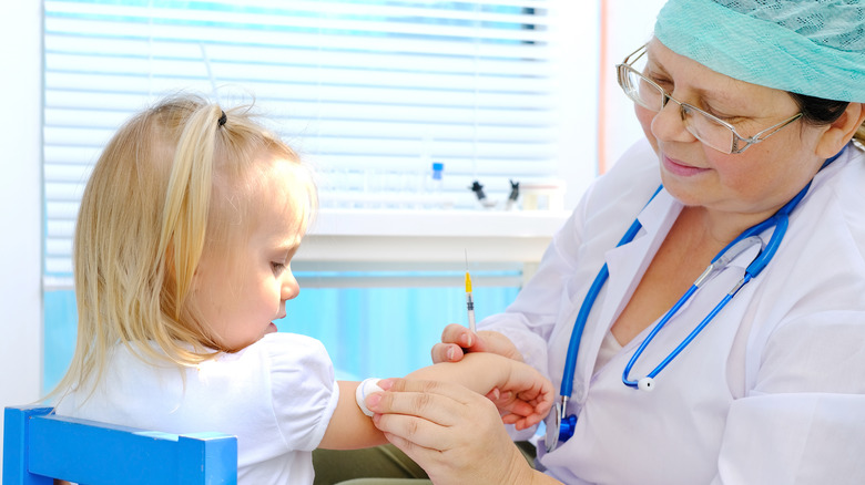 Young 2-year-old blonde girl receiving vaccine from a health practitioner