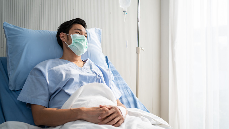 Man wearing mask in hospital bed