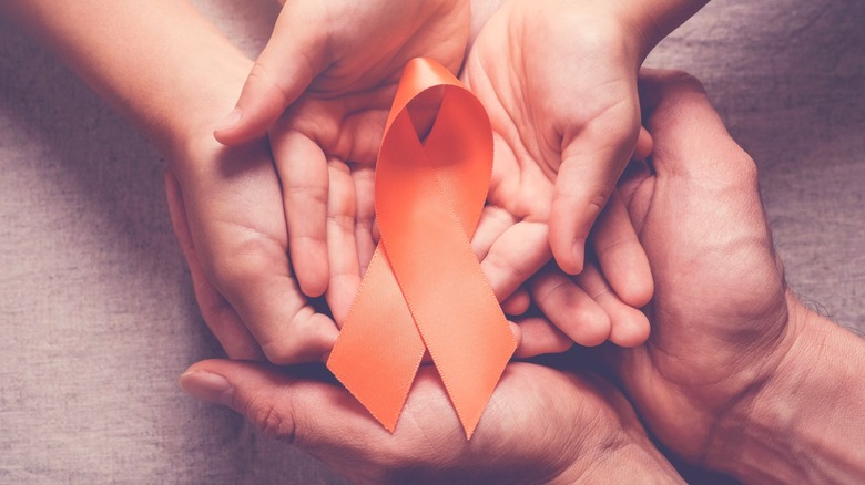 Hands holding orange Multiple Sclerosis ribbon