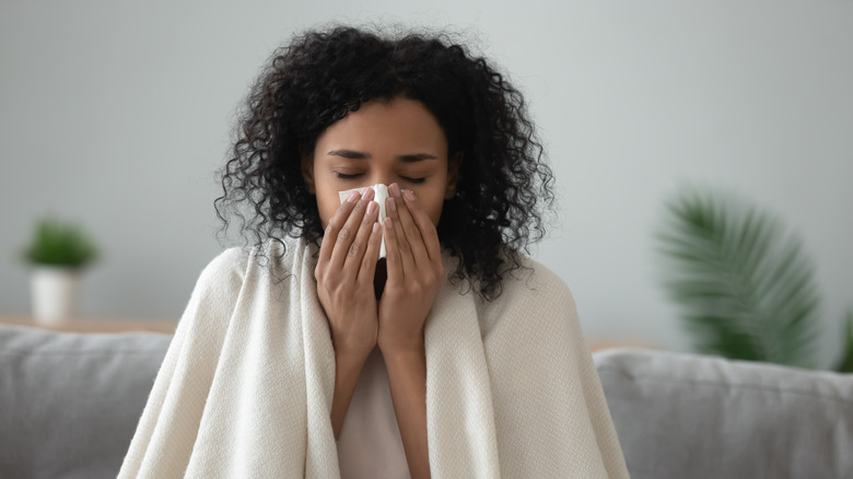 Woman recovering from runny nose on couch