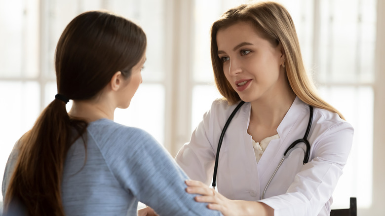 Doctor putting her hand on a female patient's arm