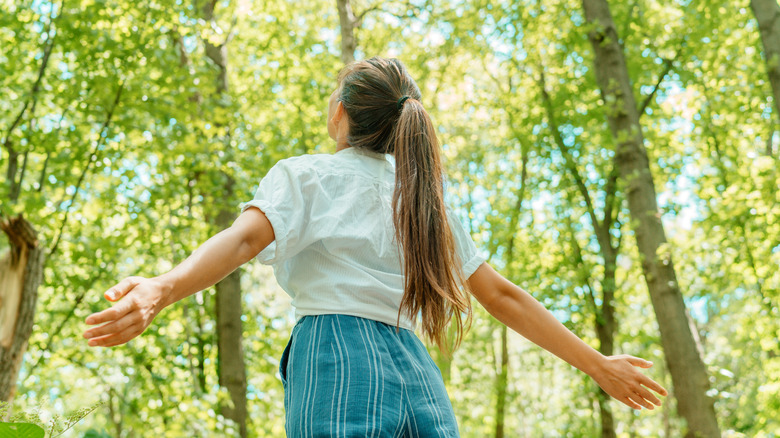 woman feeling happy breathing in clean fresh air in forest