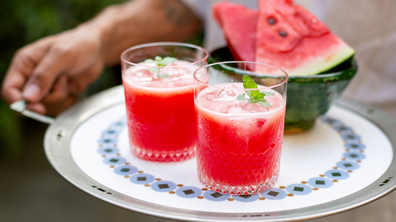 waiter holding two glasses of pink watermelon drinks
