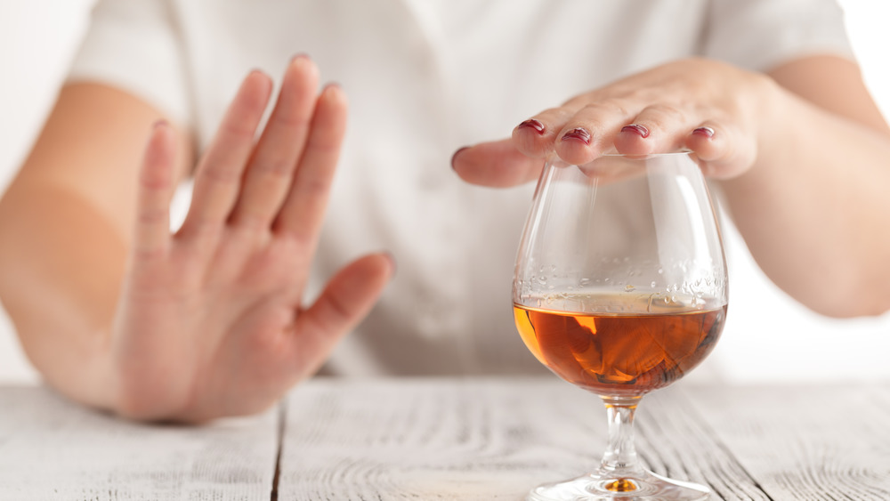 woman holding hand over wine glass