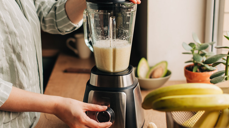 woman making almond milk smoothie in blender