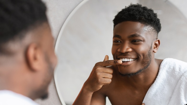 Man looking at teeth in mirror