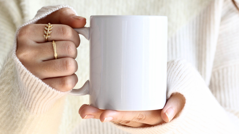 Close up on a pair of hands holding a white mug