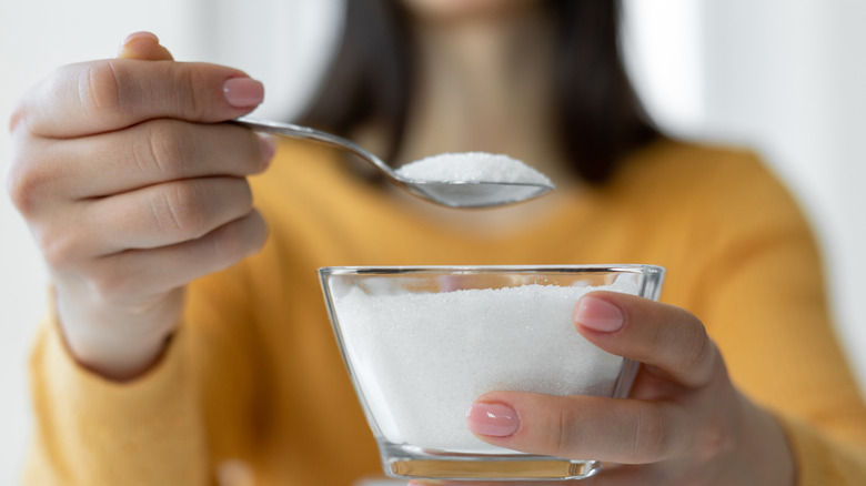 woman holding spoonful of sugar