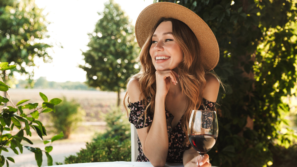 Smiling woman outside holding a glass of red wine 