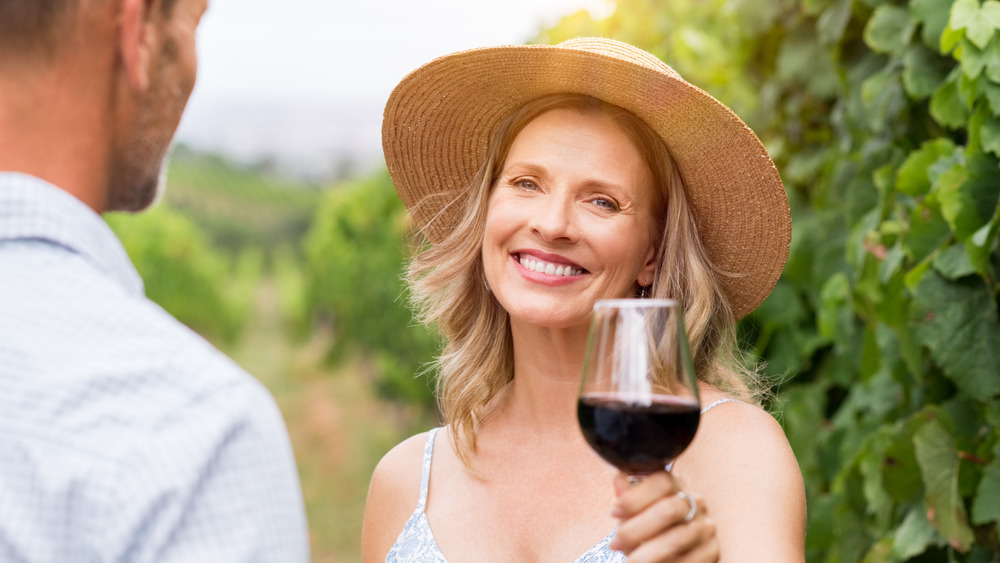 Senior woman holding up a glass of wine and smiling 