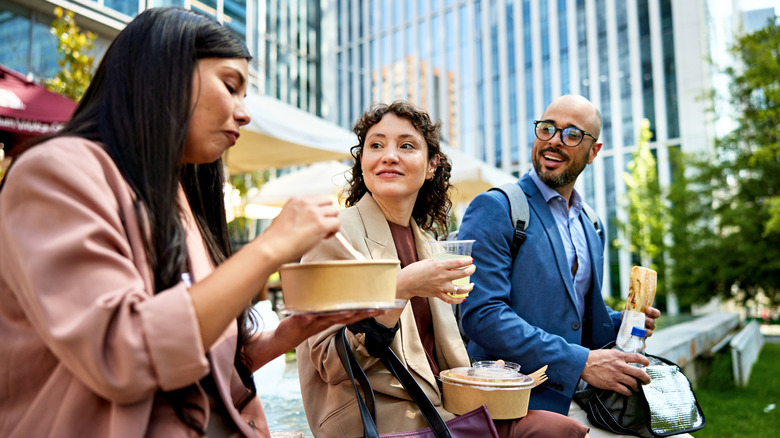 two women and man eating in a park