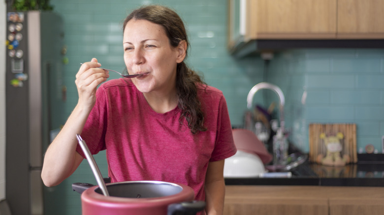 woman tasting what she's cooking in a pot
