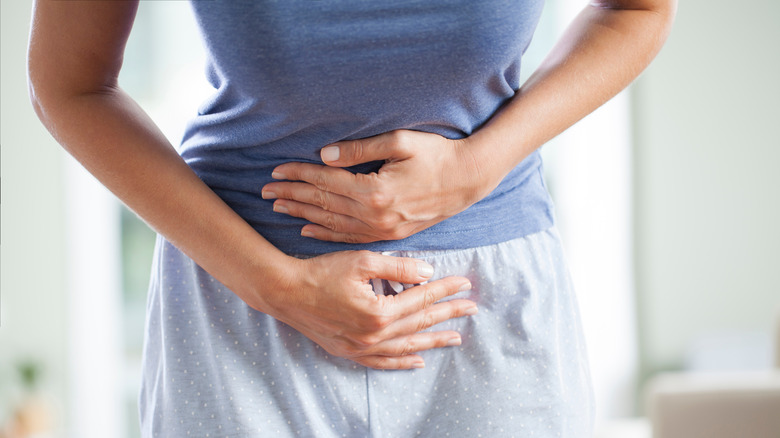 Woman is feeling bloated with her hands on her stomach