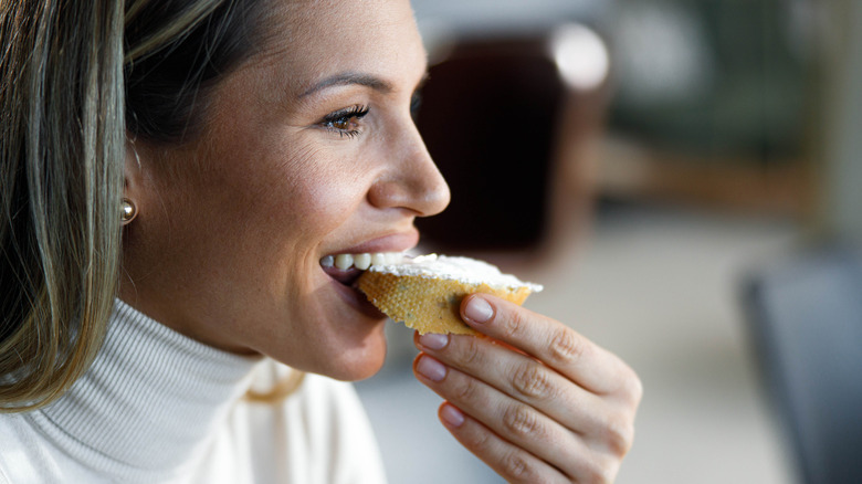 woman eating spreadable cheese on bread