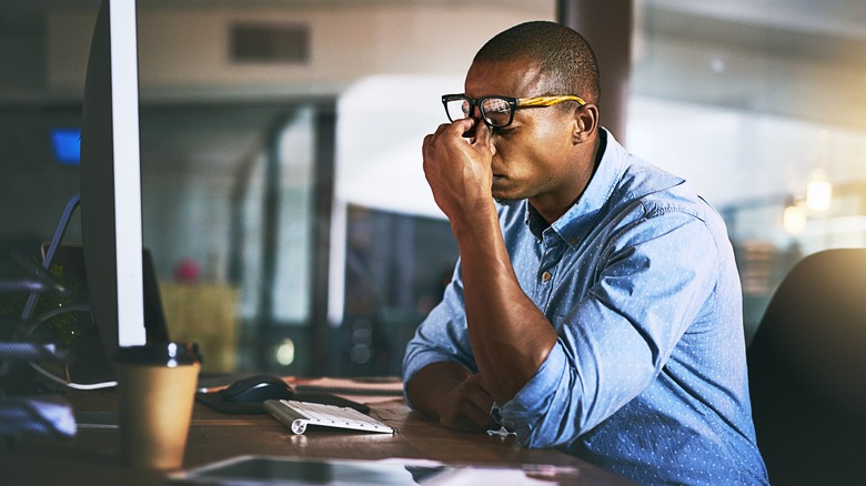 man suffering from a headache while at his desk