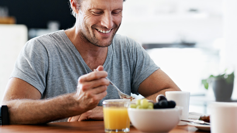 man smiling while eating breakfast