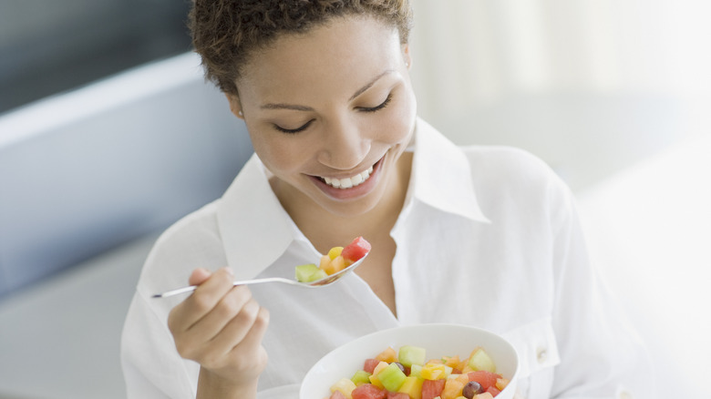 woman eating a bowl of fruit