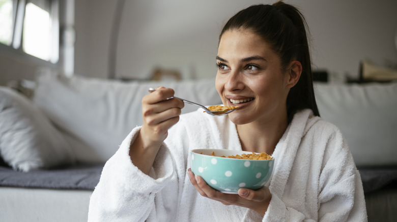 woman eating cereal in her bathrobe