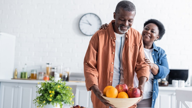 Man picking up fruit bowl in kitchen