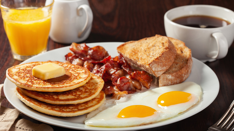 stack of pancakes with bacon, eggs, and toast