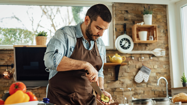 man holding a sliced avocado