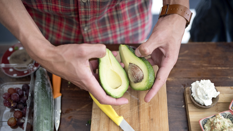 Pair of hands opening avocado
