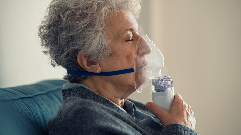 older woman breathing through mask at home