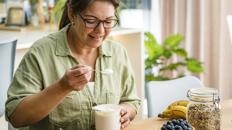 Woman spooning Greek yogurt with blueberries