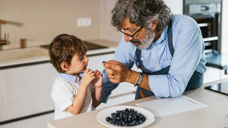 Grandfather feeding his grandson blueberries