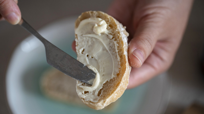 Hands spreading butter on bread