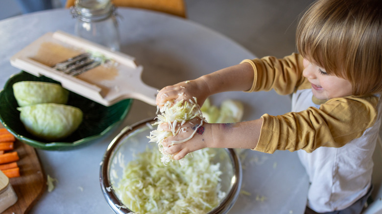 child grasping a handful of chopped cabbage